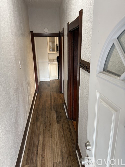 A hallway with a white door and a white wall.