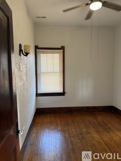 A room with a ceiling fan and a window with blinds.