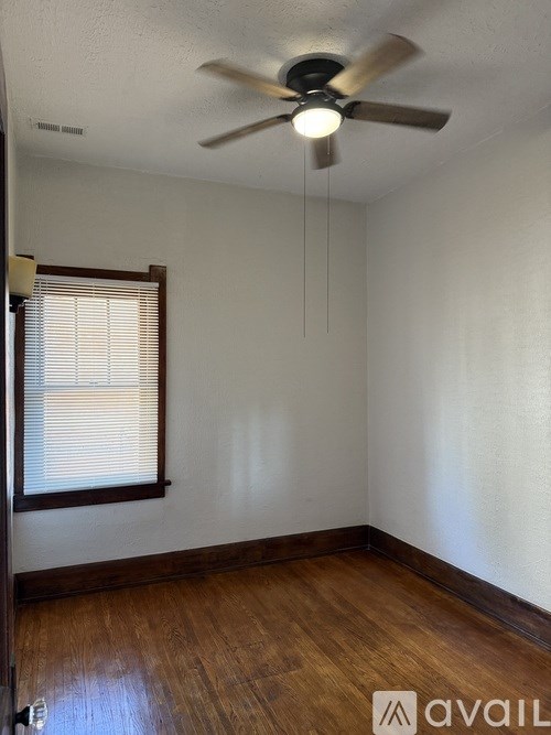 A room with a ceiling fan and a window with blinds.