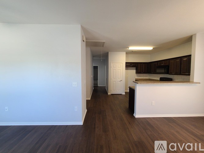 A spacious living room with a kitchen area in the background.