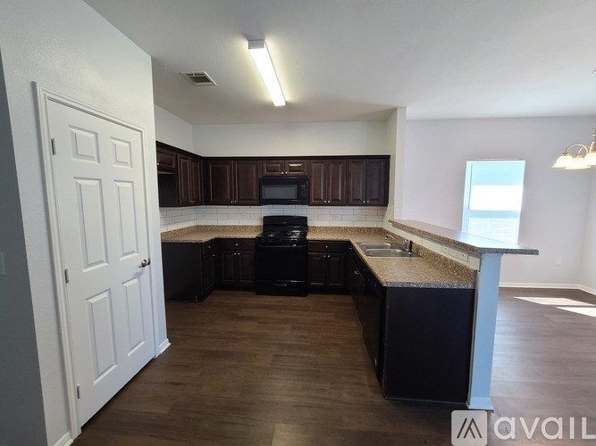 A kitchen with dark brown cabinets and a black dishwasher.