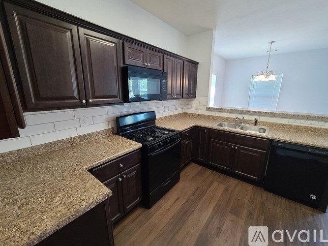 A kitchen with dark brown cabinets and a granite countertop.