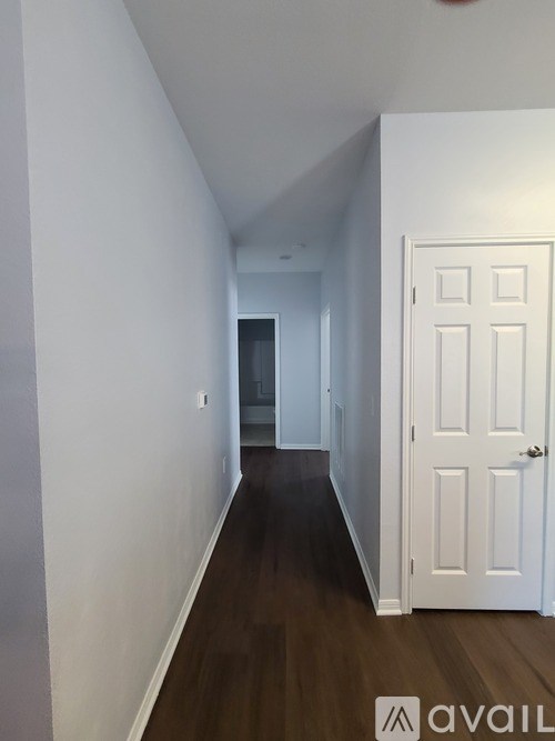 A hallway with a white door and wooden floors.