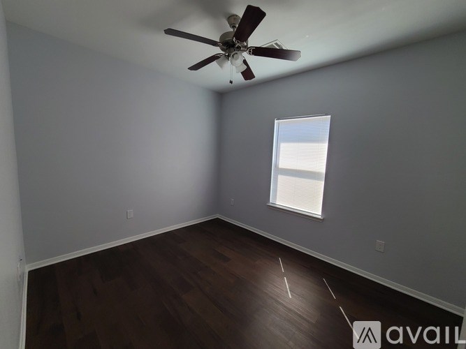 A room with a ceiling fan and a window with blinds.