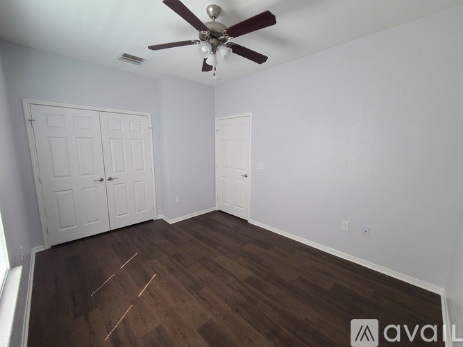 A room with a ceiling fan and wood flooring.