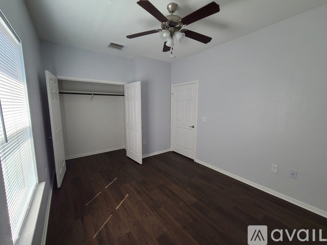 A room with a ceiling fan and wooden flooring.