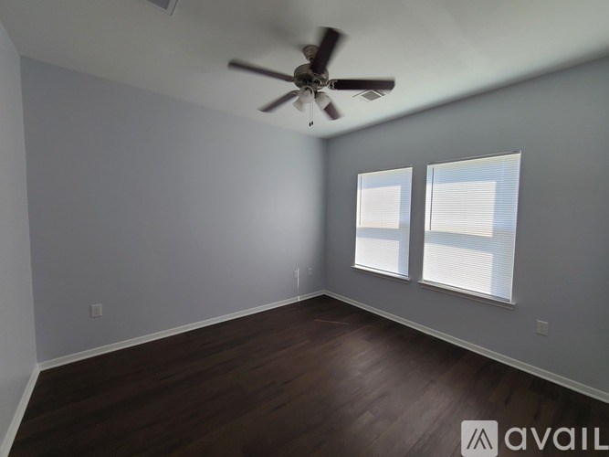 A room with a ceiling fan and two windows.