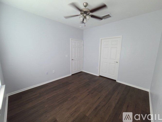 A room with a ceiling fan and two doors.