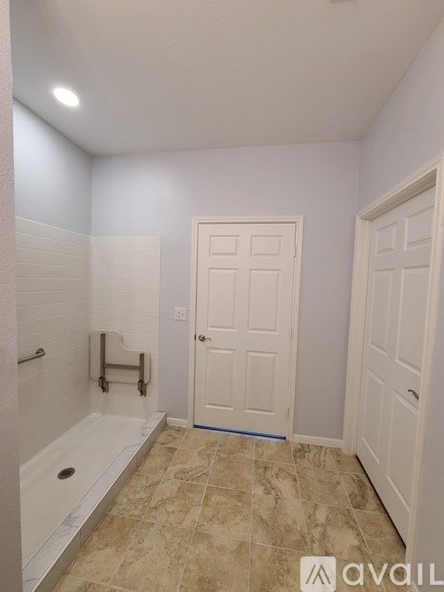 A bathroom with a tiled floor and a white door.