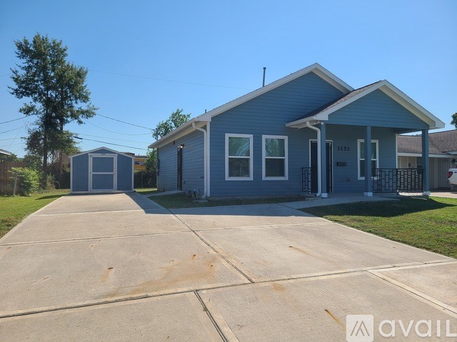 A blue house with a driveway in front.