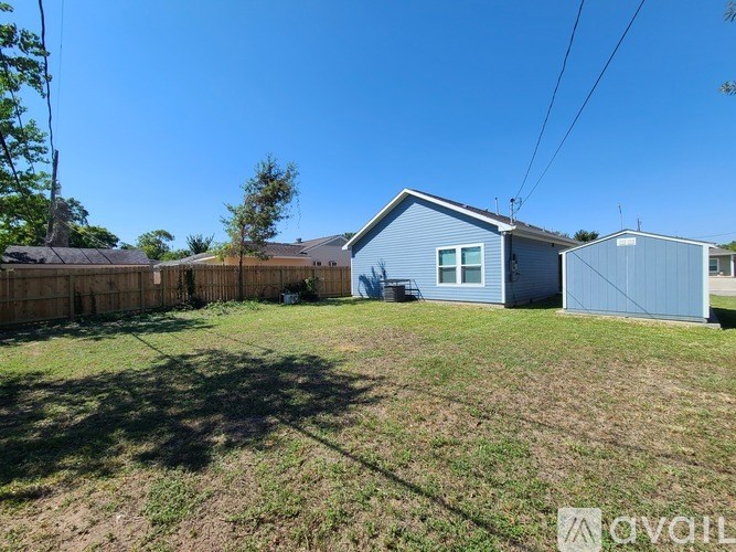 A blue house with a fence and a tree in front of it.