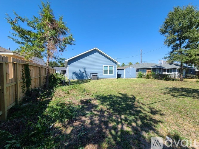 A blue house with a wooden fence and green grass in front.
