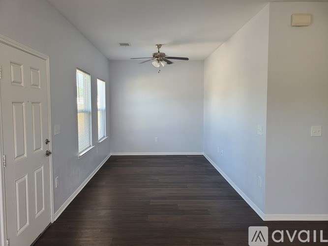 A room with a ceiling fan and wooden flooring.
