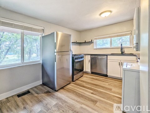 A kitchen with a stainless steel refrigerator and wooden flooring.