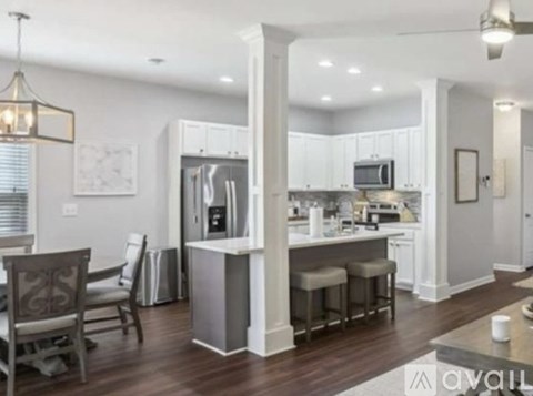 A modern kitchen with white cabinets and a wooden floor.