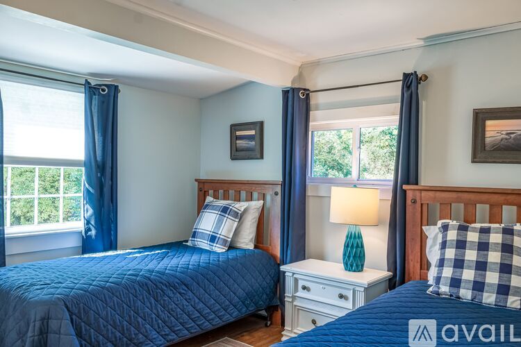 A bedroom with a blue bedspread and a white nightstand with a lamp.