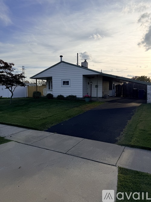 A small white house with a brown fence and a tree in front.