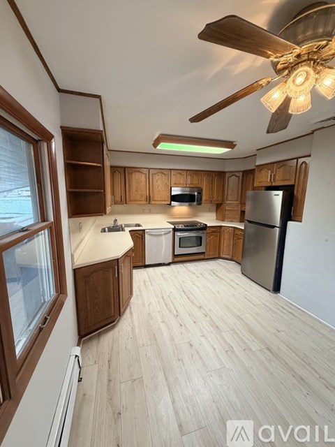 A kitchen with wooden cabinets and a ceiling fan.