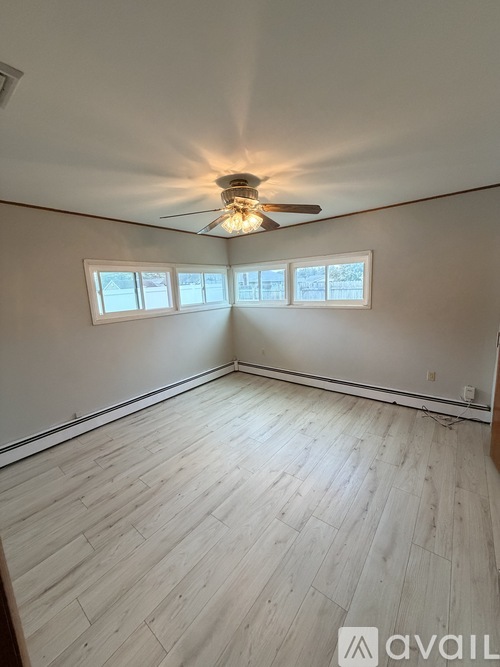 A room with a ceiling fan and three windows.