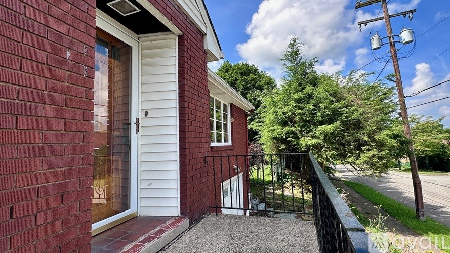 A red brick house with a white door and a black railing.