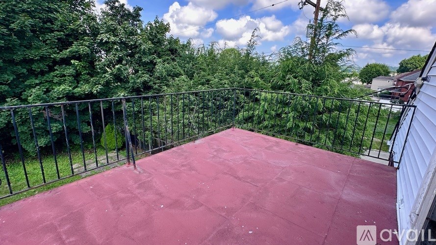 A red patio with a black railing and trees in the background.