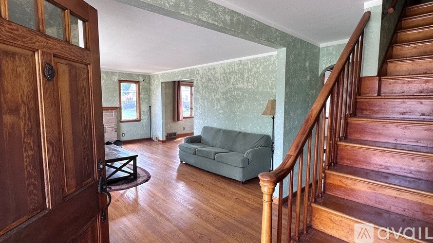 A room with a wooden staircase and a green couch.