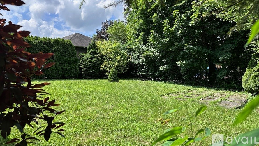 A lush green garden with a pathway and a house in the background.