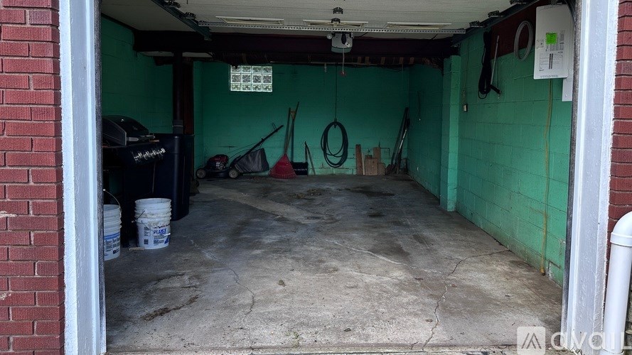 A garage with a green wall and a white bucket on the floor.