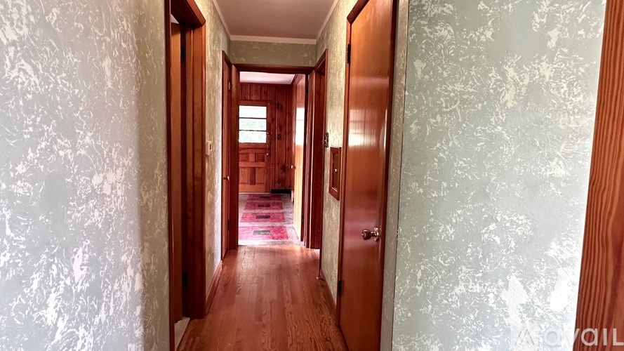 A hallway with wooden floors and doors on both sides.