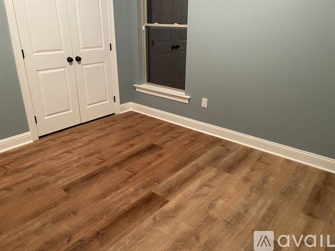 A room with a wooden floor and a white door.