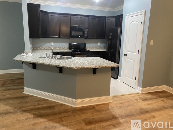 A kitchen with a granite countertop and black cabinets.