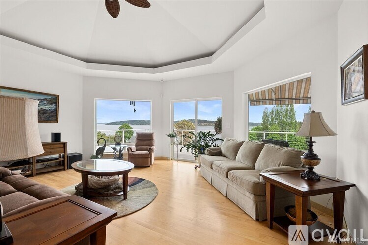 A spacious living room with a large sofa, a coffee table, and a view of the outdoors through the windows.