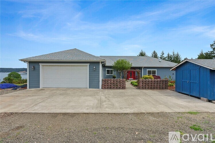 A two-story house with a garage and a blue shed.