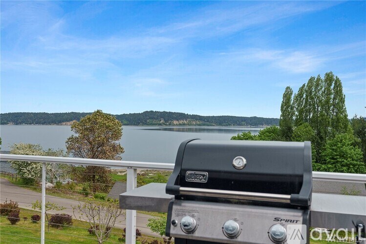 A grill is on a balcony overlooking a lake.