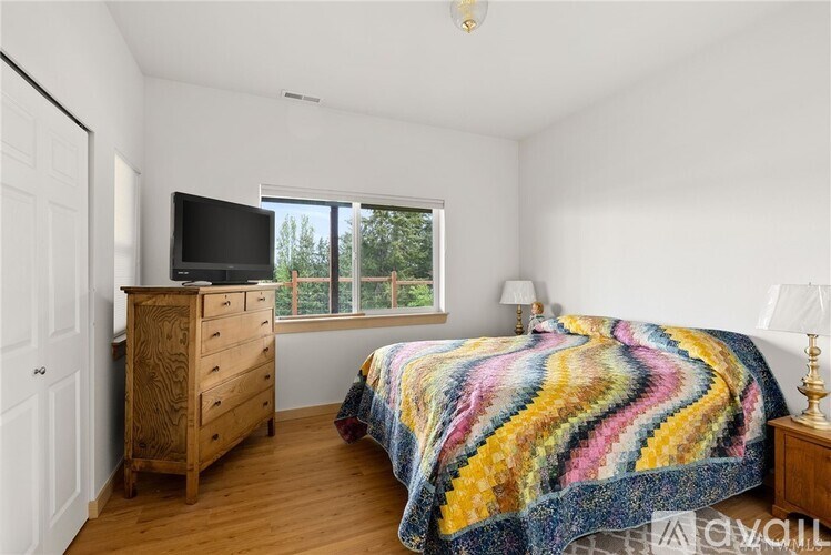 A bedroom with a bed, a dresser, and a window.