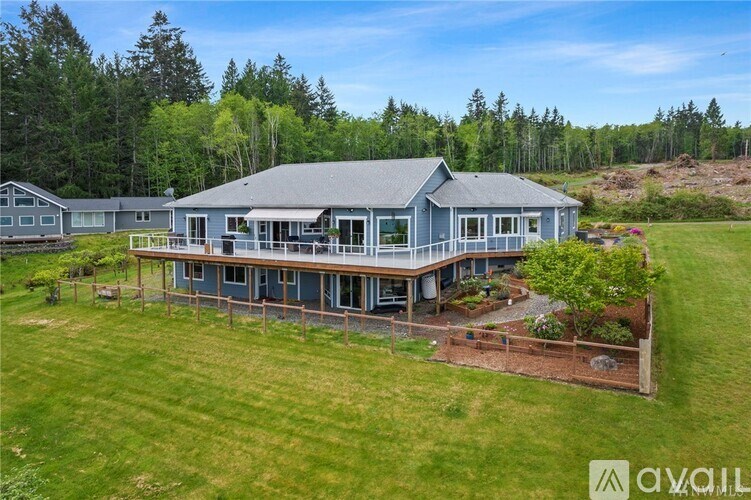 A large house with a grey roof and a deck surrounded by a grassy area.