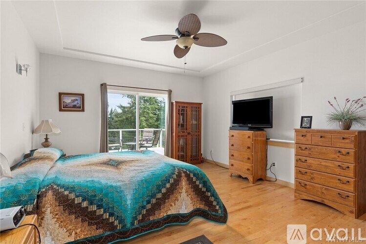 A bedroom with a bed, dresser, and a ceiling fan.