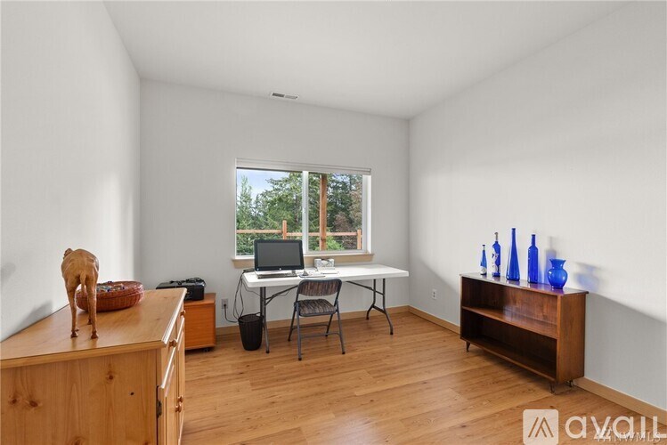 A room with a wooden floor and a window with a view of trees outside.