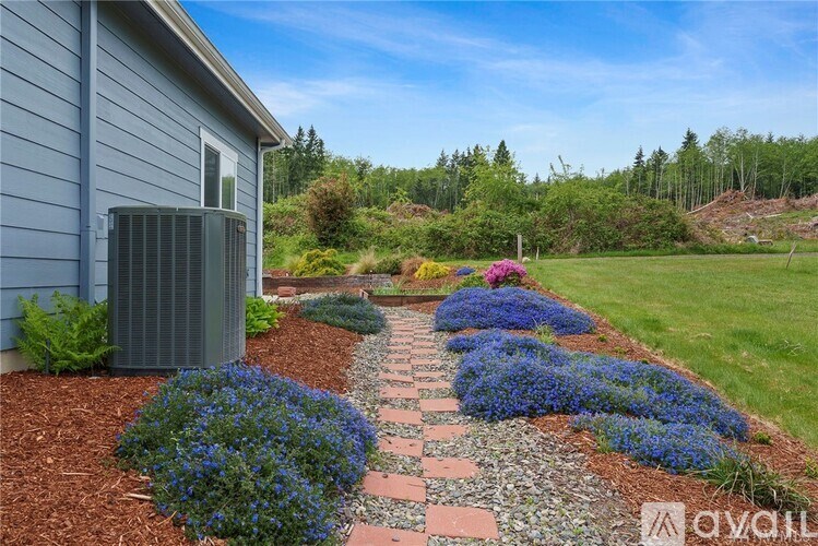A garden pathway with blue flowers on either side leads to a house.