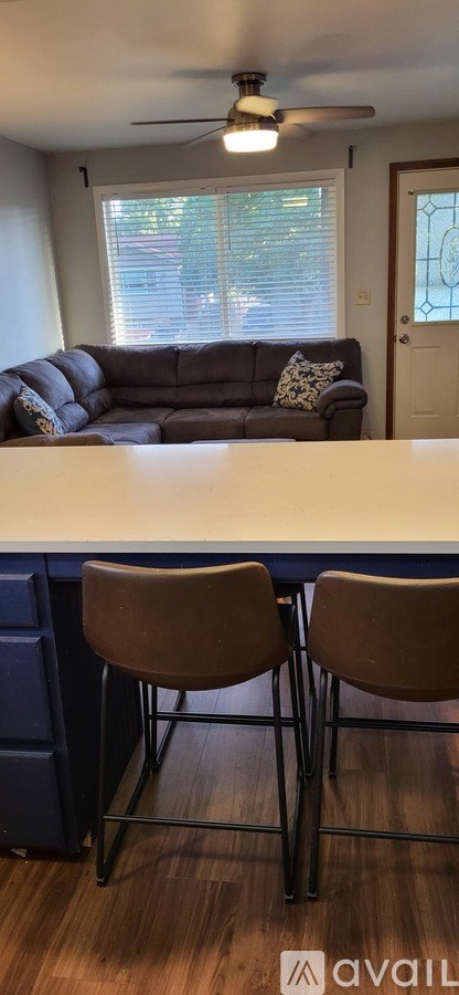 A living room with a grey couch and a ceiling fan.