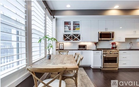 A kitchen with white cabinets and a wooden table.