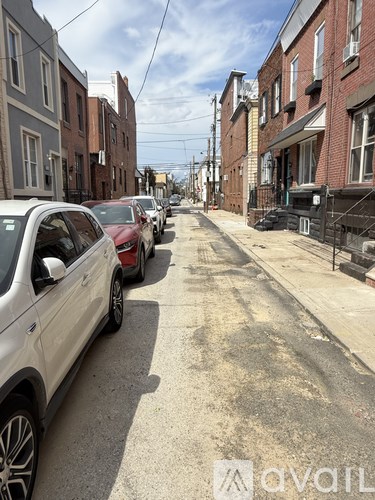 A white car is parked on the left side of a street with other cars parked on the right side.