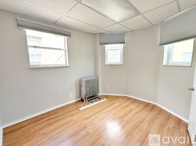 A room with wooden floors and a window with blinds.