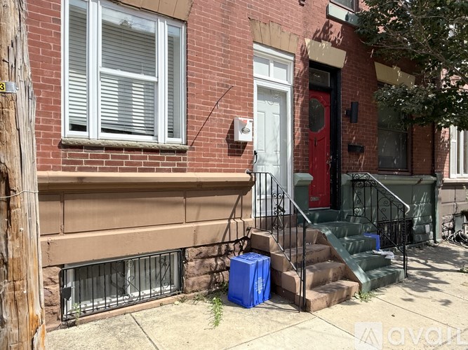 A red brick house with a blue cooler on the front steps.