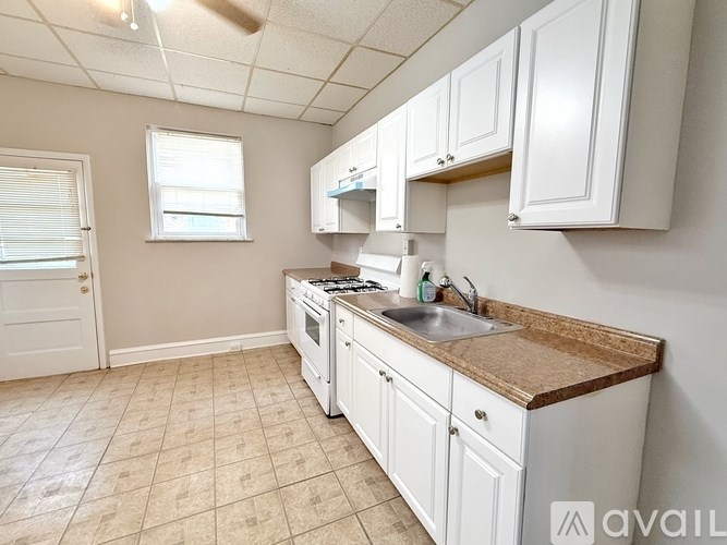 A kitchen with white cabinets and a brown countertop.