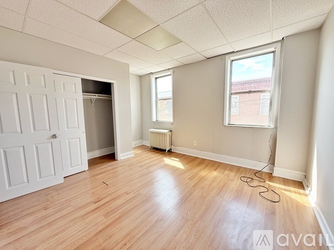 A room with a white door and a window with a radiator under the window.