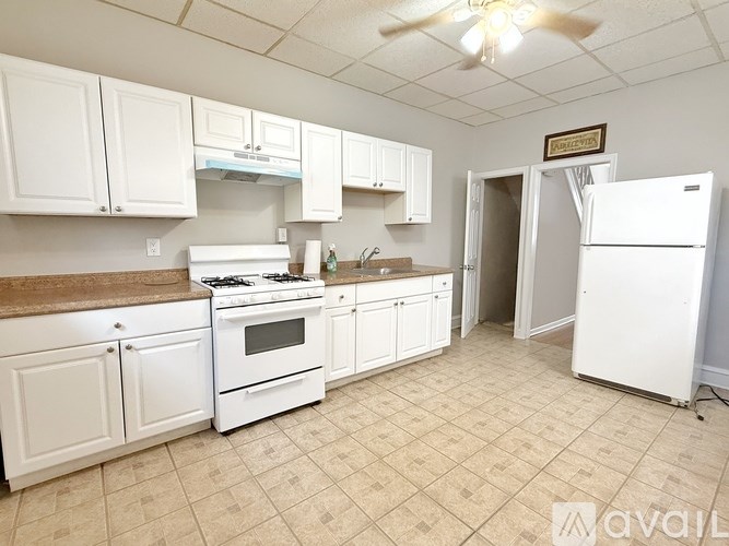 A kitchen with white appliances and cabinets is available for rent.