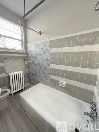 A room with wooden flooring and a staircase with a carpeted runner.