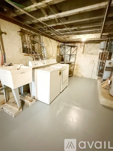 A room with wooden flooring and white walls, with a door open to another room.