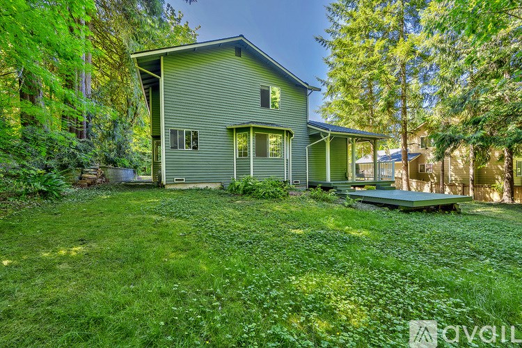 A house with a green lawn and trees in the background.